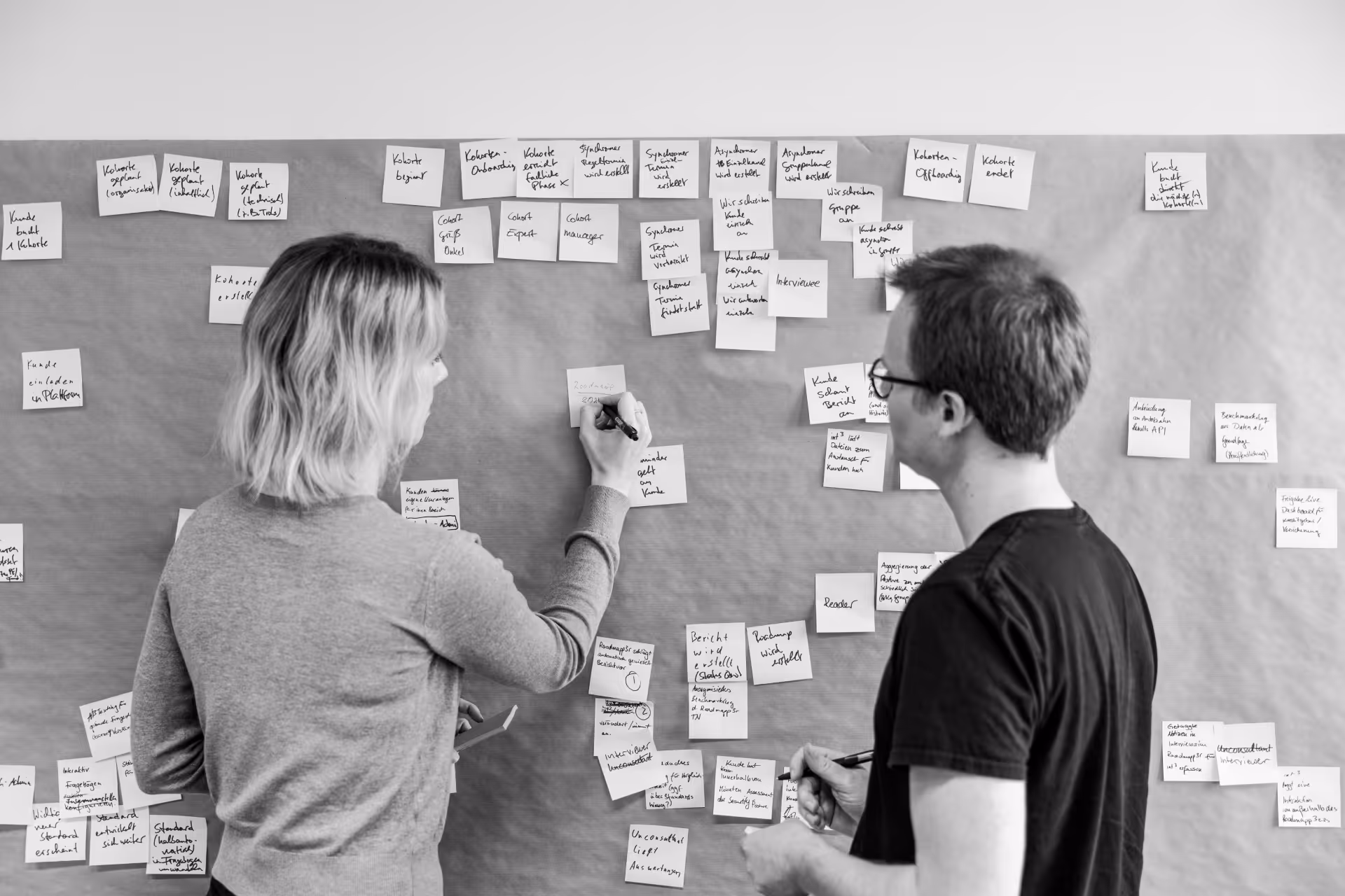 Zwei Mitarbeitende von intcube beim Workshop vor einer Pinnwand mit vielen Post-its.