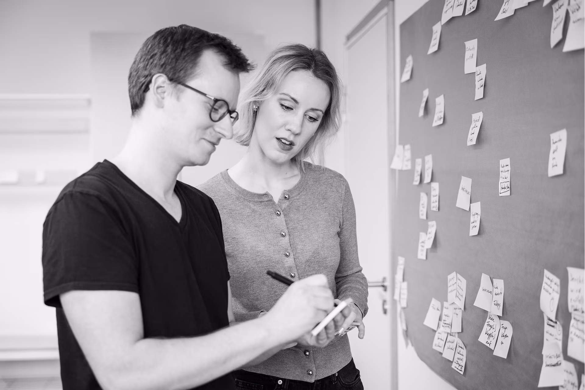 Zwei Mitarbeitende von intcube bei einem Workshop mit Post-its an der Wand